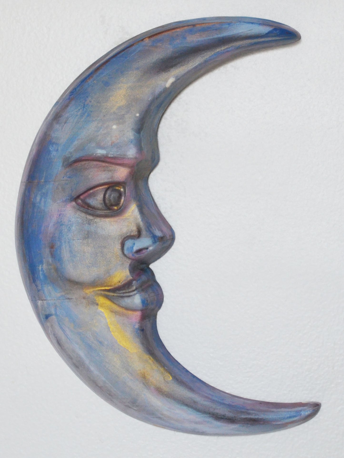 Decorative wall art of a half-moon with a face on a white background