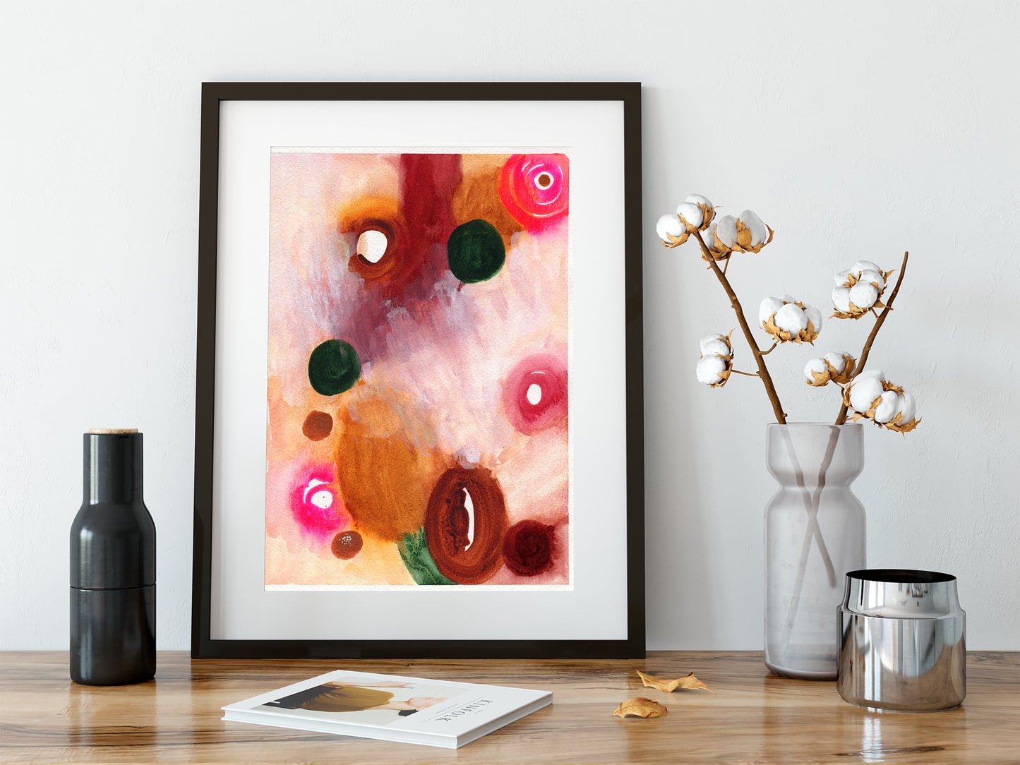 Framed abstract art piece on a wooden surface with decorative items.