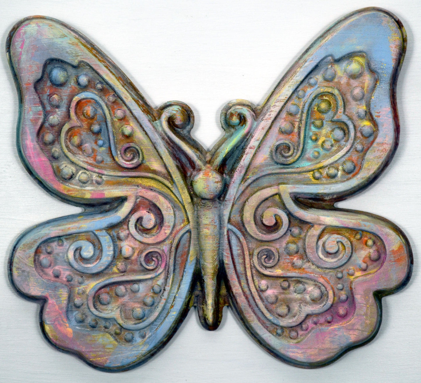 Hand painted 3d wood carving of a butterfly with swirl heart design, finished with a wax topcoat in pastel colors.