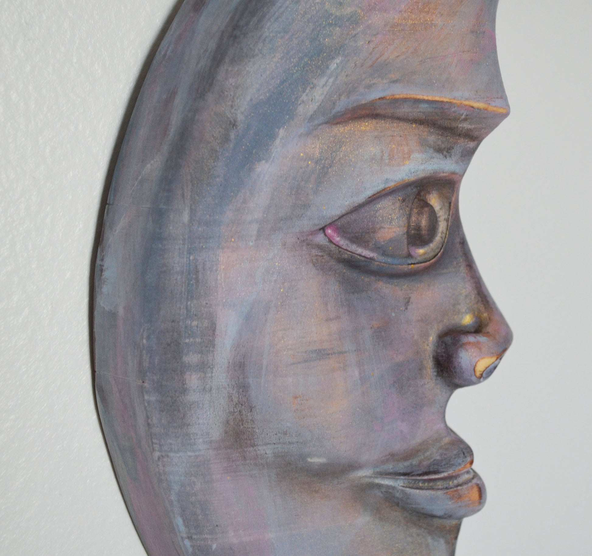 Metallic wall art of a stylized face on a plain background