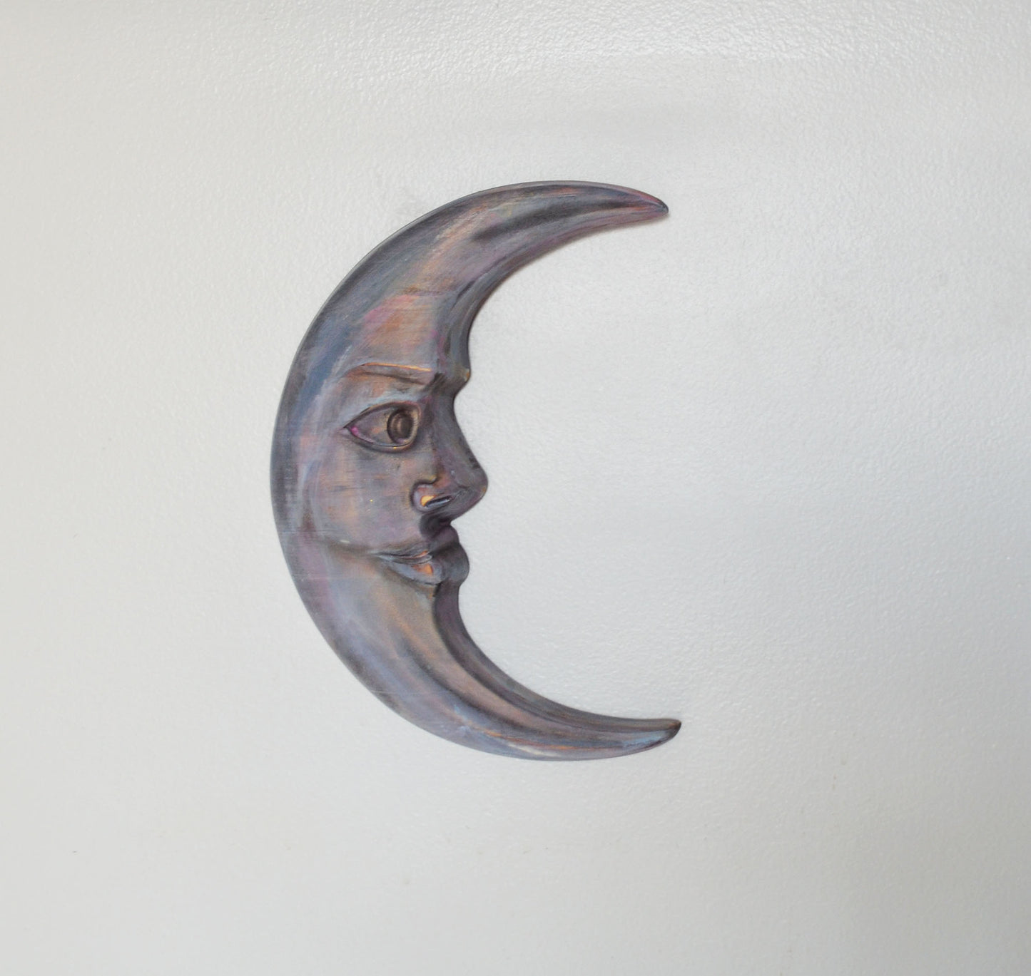 Decorative metal crescent moon with face on a light gray background