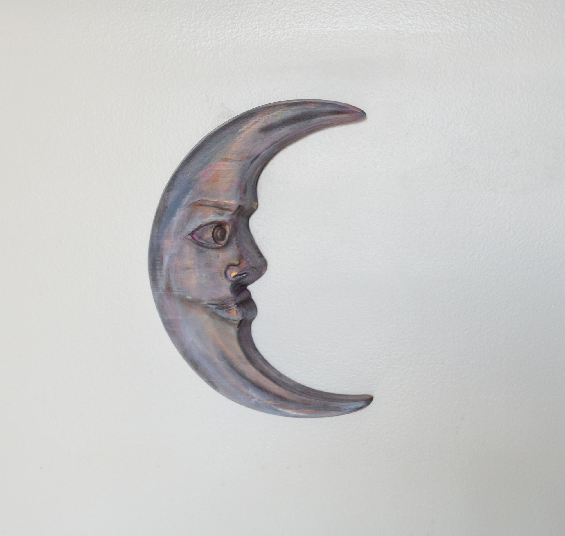Decorative metal crescent moon with face on a light gray background