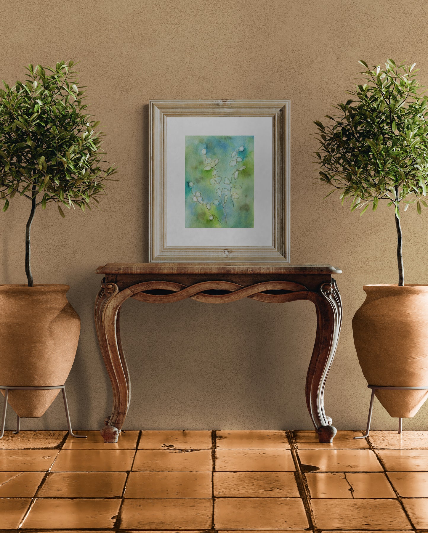 Decorative table with a framed artwork between two potted plants against a beige wall.
