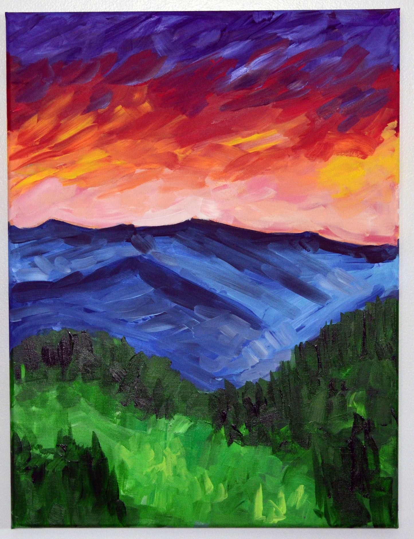 An acrylic painting on stretched canvas featuring a vibrant mountain landscape with a red and blue sky and green forested mountains.