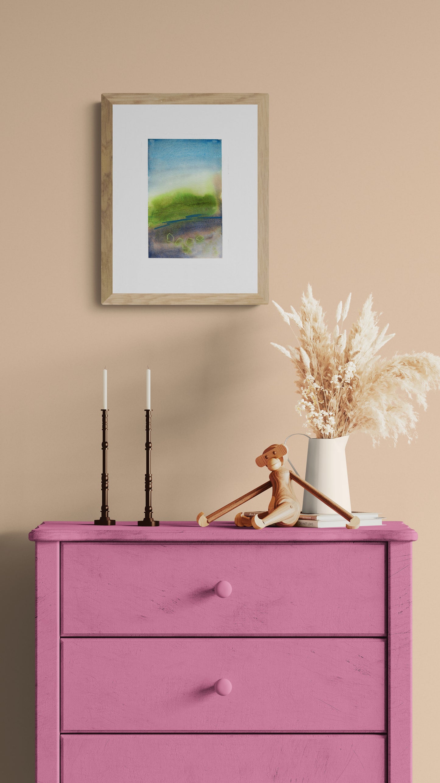 Pink dresser with decorative items against a beige wall with a framed picture.