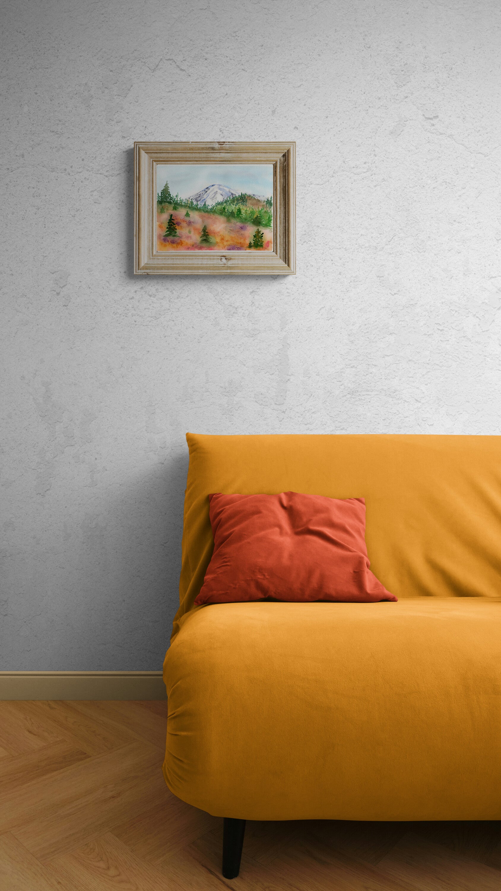 Yellow sofa with a red pillow against a gray wall with a framed picture.