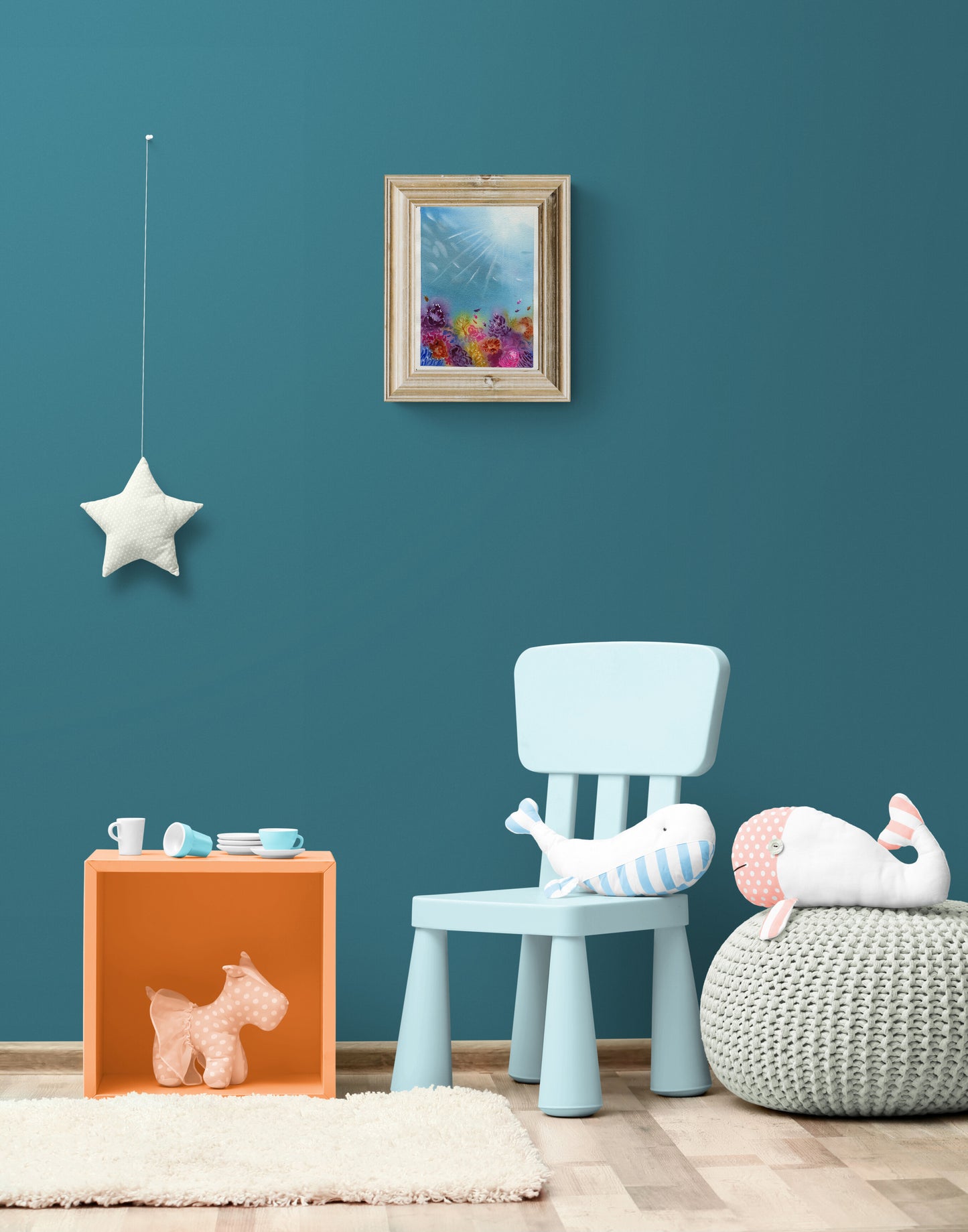 Children's room with teal walls, a blue chair, and toys on an orange box.