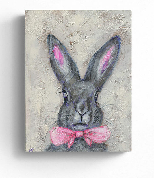 A painting on canvas featuring a stylized fluffy bunny with a pink bowtie and black ears, with a blurred background.