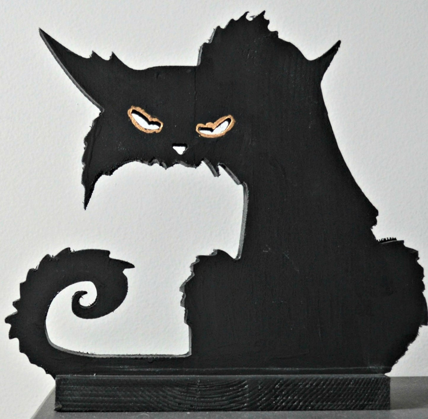 A 3D wood carving of a black cat with a spooky expression, featuring a dark body and orange eyes, intended for Halloween decoration.
