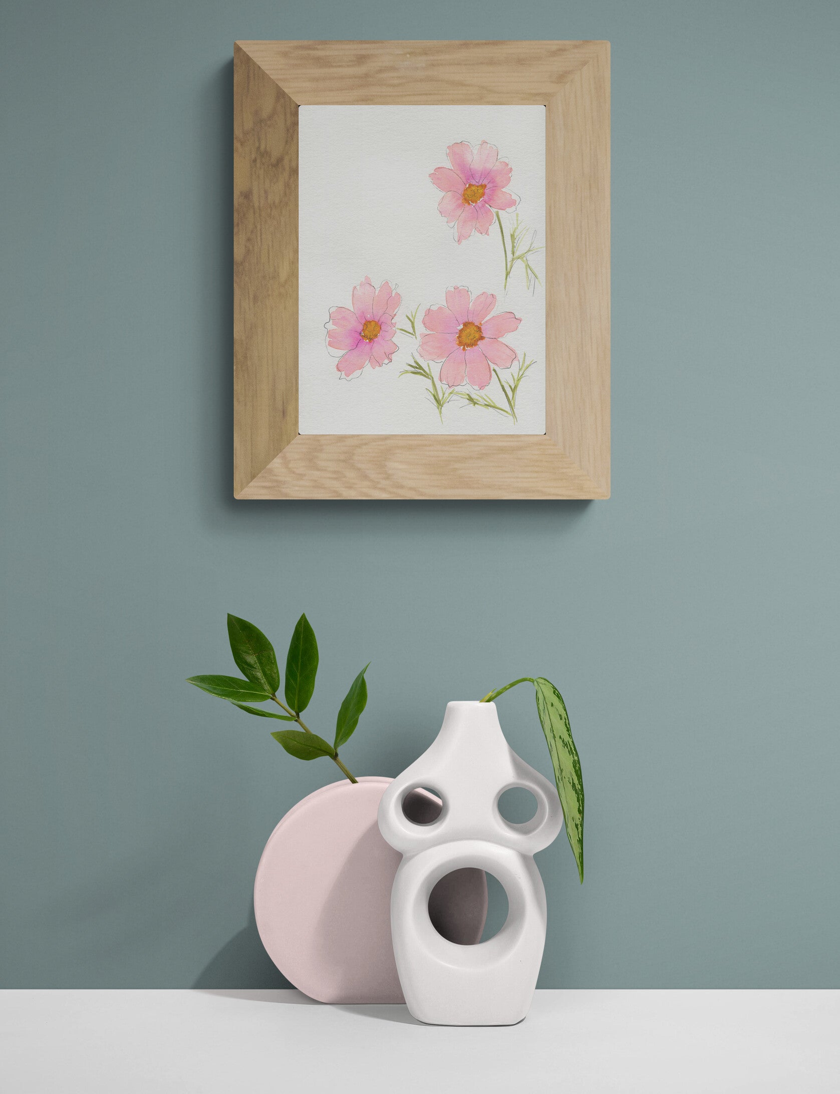 Framed artwork of pink flowers on a gray wall with two ceramic vases below.
