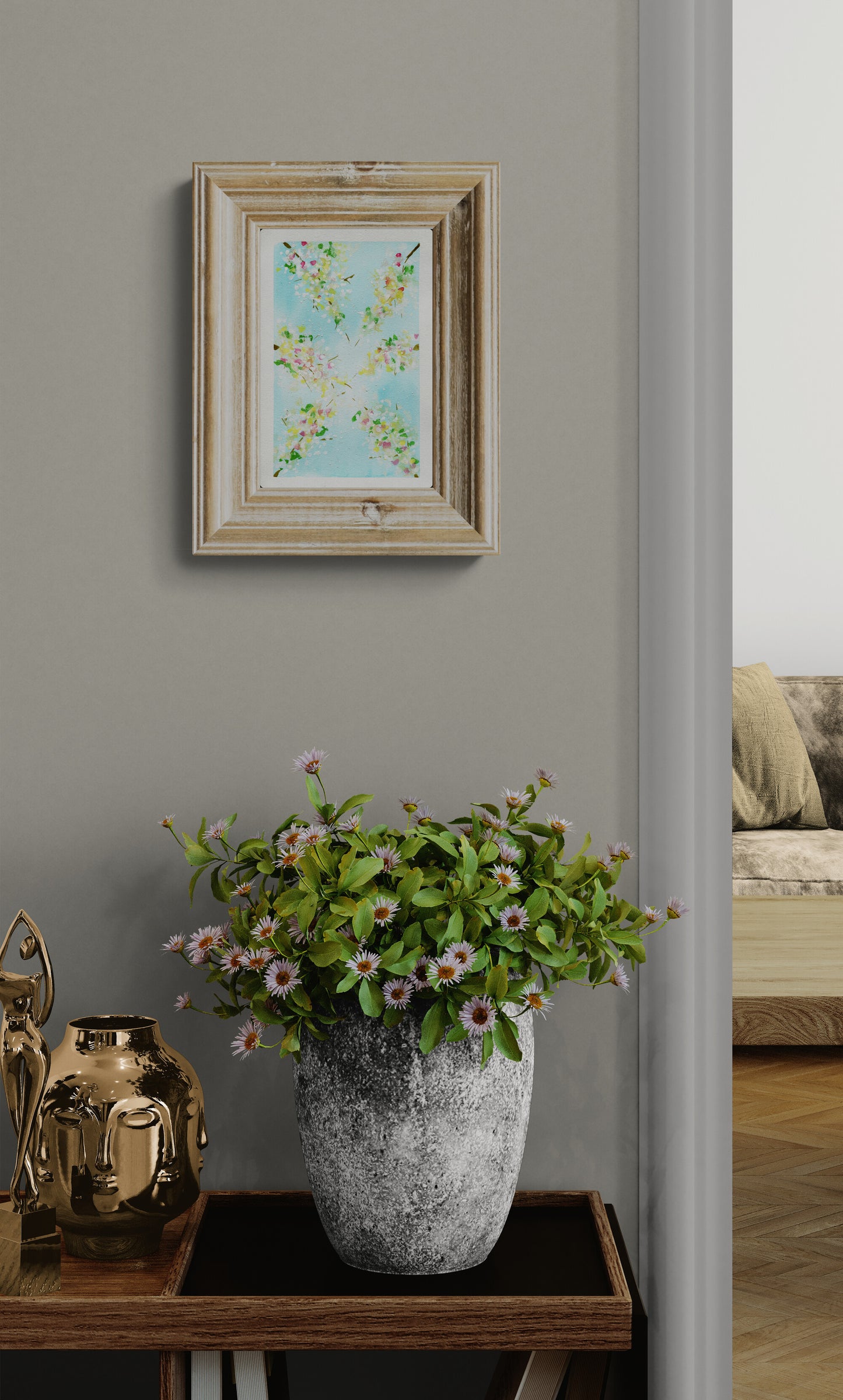 Framed artwork on a wall with a vase of flowers on a table below.