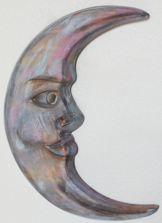 Decorative wall art in the shape of a crescent moon with a face on a white background